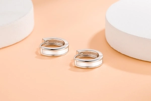 Macro detail of silver geometric hoop earrings with white enamel drip oil finish