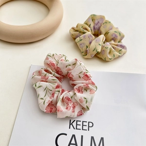Detail of floral chiffon hair scrunchies in pink and yellow on a clean desk background
