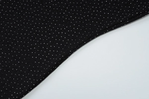 Vue macro de strass argentés étincelants sur un tissu de robe noire élégante et ajustée