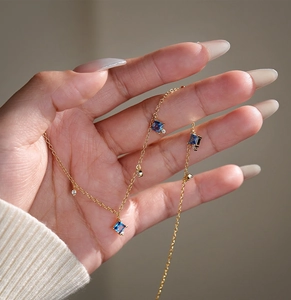 Close-up of gold S925 silver necklace with blue square zircon and clear crystals