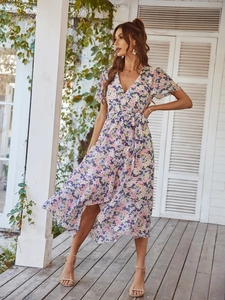 Détail d'une robe longue fleurie à col en V avec ceinture sur terrasse en bois