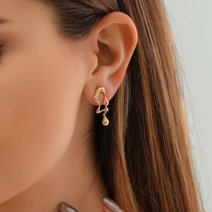 Close-up of gold irregular liquid drop earrings on a model showing molten lava design
