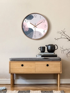 Modern abstract round wall clock with rose gold frame on a beige wall in a living room