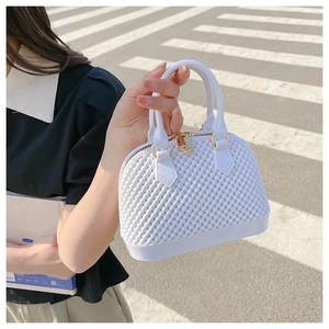 Detail view of a white bubble texture shell bag with golden zipper and handle