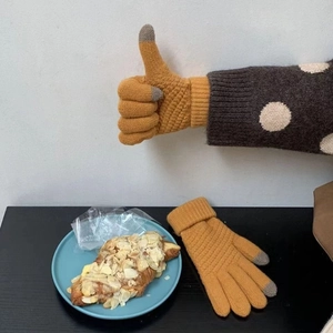 Close-up of ginger yellow knit touchscreen gloves with grey fingertips on a table