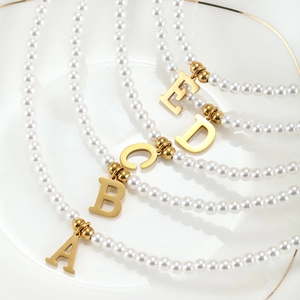 Detail of elegant pearl necklaces featuring gold-toned A to E initial pendants on a dish