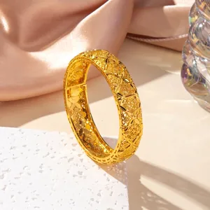 Macro detail of vintage hollow flower pattern on golden open bangle over stone