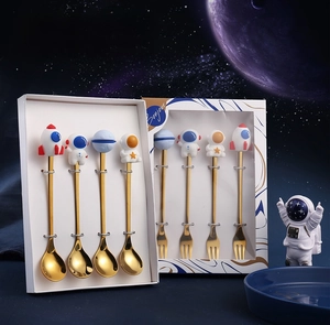 Macro shot of golden astronaut themed stainless steel spoon and fork set in gift box