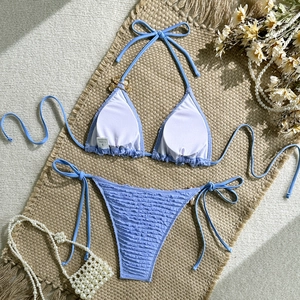 Detail shot of light blue crinkle fabric bikini on a summer resort straw mat setup