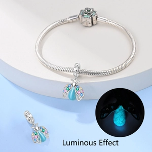 Detailed view of silver charm bracelet featuring a luminous green flower and firefly pendant
