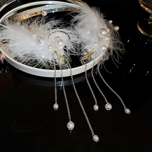 Detail of white feather ear cuffs with imitation pearls and long silver tassels