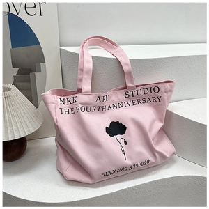 Detail of pink canvas tote bag with black floral print and NKK Art Studio typography