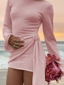 Detail of pink terry cloth mini dress with rose decoration and side ruching at sunset