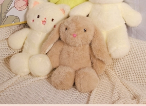 Detail of plush brown bunny and white cat dolls on a soft knitted blanket