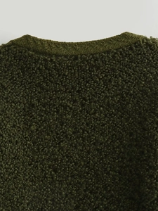 Detailopname van donkergroene bouclé-gebreide stof en afwerking van de halslijn