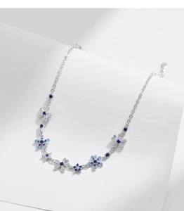 Macro detail of 925 silver bracelet with blue gradient floral charms and zircon stones