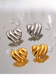 Gros plan de boucles d'oreilles cœur en or et argent avec texture métallique ondulée