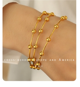 Close-up of three gold beaded minimalist stainless steel bracelets on a female wrist