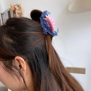 Detailed view of a blue marble acrylic dinosaur hair claw clip worn on a woman's bun