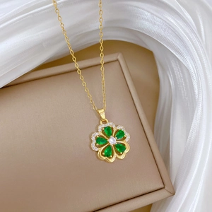 Detail of a golden floral necklace featuring green crystal petals and diamond accents