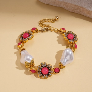 Detail of baroque pearl bracelet with pink gemstone flower and golden chain finish