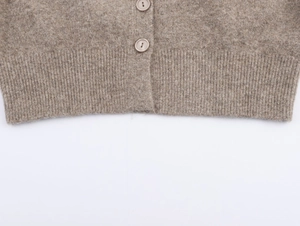 Detail of oatmeal knit cardigan showing textured fabric, buttons and ribbed hem