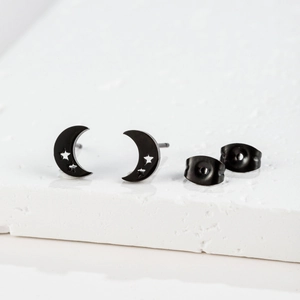 Detail view of black stainless steel moon and star stud earrings on white stone