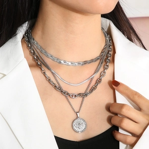 Close-up of silver multilayer necklace with bee pendant and pig nose chain detail