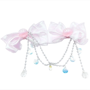 Détail de barrettes nœuds roses avec breloques coquillage et chaînes de perles irisées
