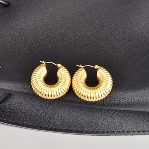 Classic golden croissant hoop earrings with ribbed texture on black leather background