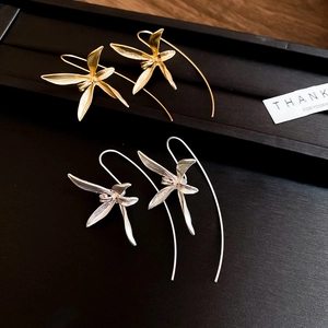 Detail of gold and silver orchid petal earrings on a black textured display plate