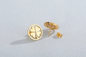 Detail of gold four-leaf clover stud earring with sparkling rhinestone and polished finish
