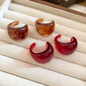 Chic resin C-shaped hoop earrings in amber tortoiseshell and burgundy on beige tray