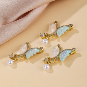 Detailed view of golden butterfly charms with iridescent shell wings and hanging white pearls