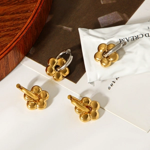 Detailed view of floral 18k gold plated stainless steel hoop earrings on a tray
