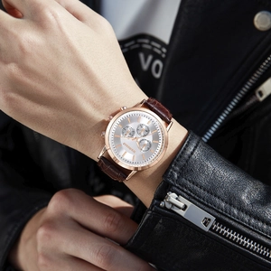 Fashionable men's watch with gold case, white dial, and brown leather strap on model