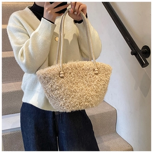 Gros plan sur un sac à bandoulière en peluche blanc cassé avec de fines lanières en cuir souple
