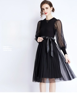 Detail of black knit dress featuring polka dot mesh sleeves and waist bow tie accent