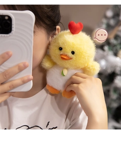 Close-up of small yellow plush chick toy with red heart and white belly held in hand
