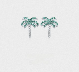 Macro shot of silver palm tree studs with green gems and white crystal pavé details