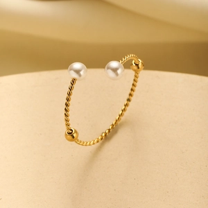 Detail of twisted 18K gold plated stainless steel open bangle with pearls and gold beads