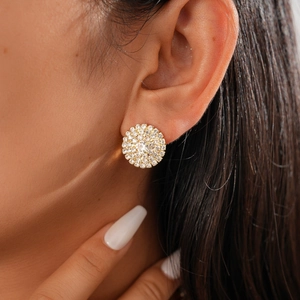 Close-up of elegant gold stud earrings featuring a circular cluster of sparkling crystals