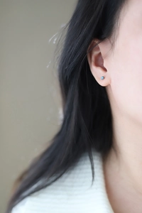 Close-up of a minimalist silver titanium earring with a sparkling blue round zircon stone