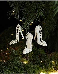 Close-up of white glitter high heel Christmas ornaments hanging on a pine tree branch