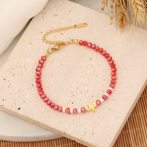 Beaded natural stone bracelet with red faceted beads and gold star charm on stone tray