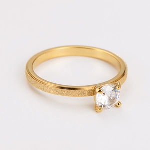Macro detail of gold frosted ring featuring a four-prong set sparkling zircon stone
