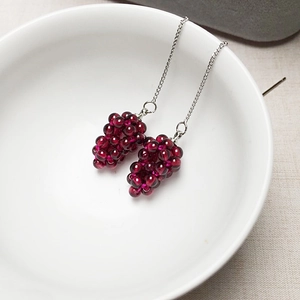 Detail of handmade garnet grape cluster earrings with long silver tassels in a ceramic bowl