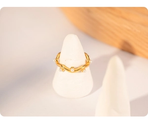 Detail of wavy gold-plated titanium ring with pearl inlays on a jewelry display