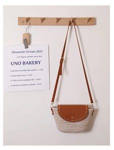 Detail of PU leather flap with gold studs on a woven straw crossbody vacation bag