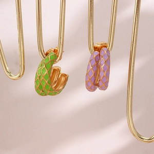 Close-up of gold stainless steel checkered earrings with green and purple enamel finish